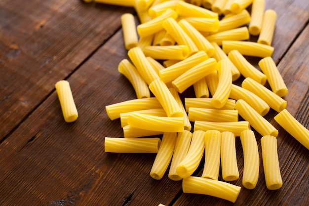 Macarrão cru para preparar almoço saudável deitado na velha mesa de madeira