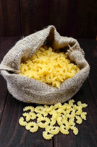 Macarrão cru pasta galetti pilha grande no saco sobre uma mesa de madeira