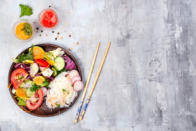 Macarrão de arroz picante e salada de legumes em fundo de pedra