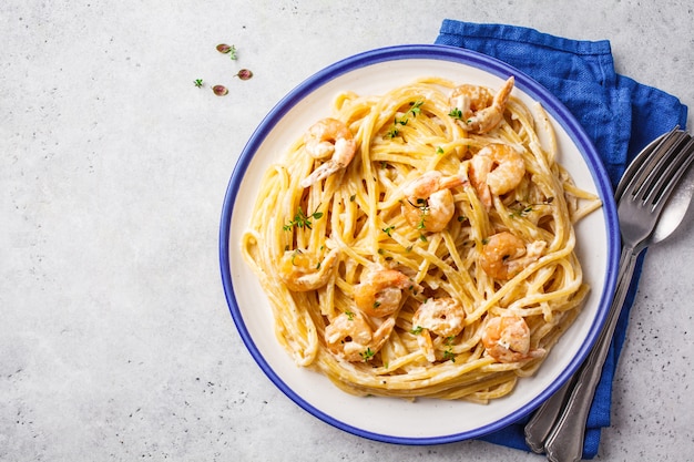 Macarrão de camarão com creme e ervas em chapa branca.