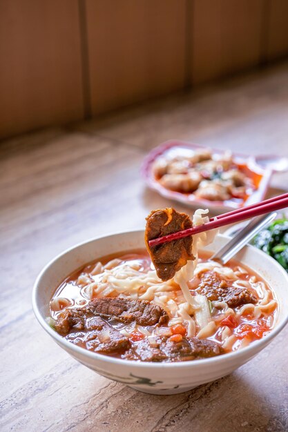 Macarrão de carne Taiwan ramen refeição com caldo de molho de tomate em tigela na mesa de madeira brilhante famosa comida de estilo chinês close-up vista superior cópia espaço