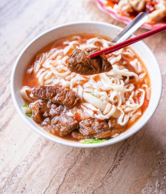 Macarrão de carne Taiwan ramen refeição com caldo de molho de tomate em tigela na mesa de madeira brilhante famosa comida de estilo chinês close-up vista superior cópia espaço