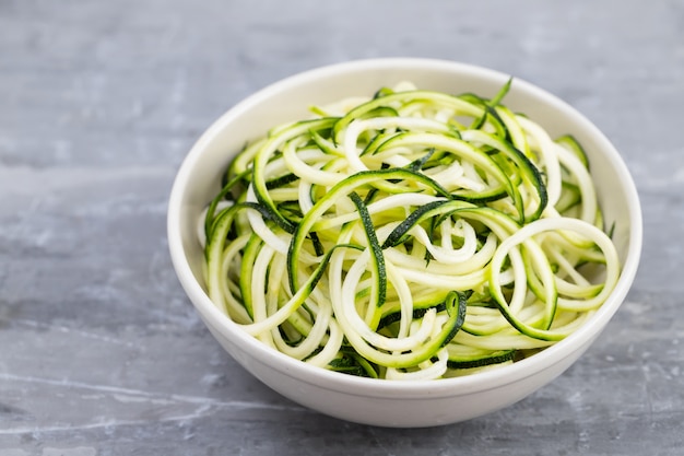 Macarrão de courgette em tigela sobre fundo cinza de cerâmica