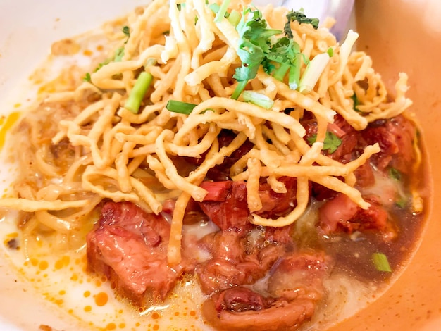 Macarrão de curry vermelho do norte tailandês closeup com ensopado de carne e macarrão de ovos fritos