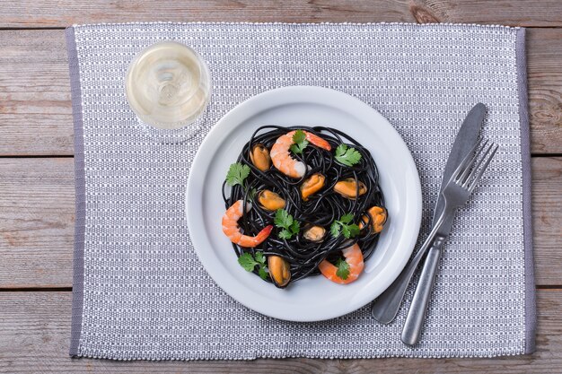 Macarrão de espaguete preto com marisco camarão mexilhões e salsa