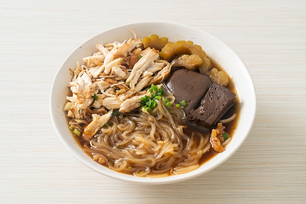 Macarrão de frango estufado em estilo de comida asiática de tigela de sopa marrom