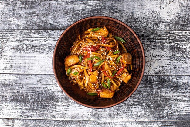 Macarrão de frango wok em um fundo branco de madeira