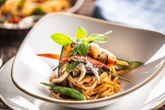 Macarrão de linguini vegetariano com berinjela, ervilha, cenoura, pimenta e manjericão.