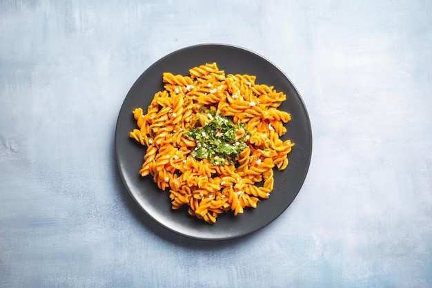 Macarrão de macarrão encaracolado com molho de tomate e gremolata em um prato redondo escuro sobre uma mesa