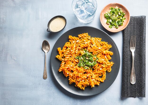 Macarrão de macarrão encaracolado com molho de tomate e gremolata em um prato redondo escuro sobre uma mesa