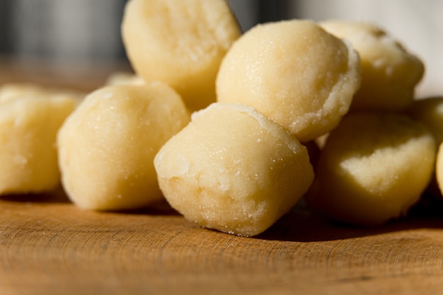 Foto macarrão de nhoque pré-cozido em uma placa de madeira com queijo ralado macro close-up foco seletivo