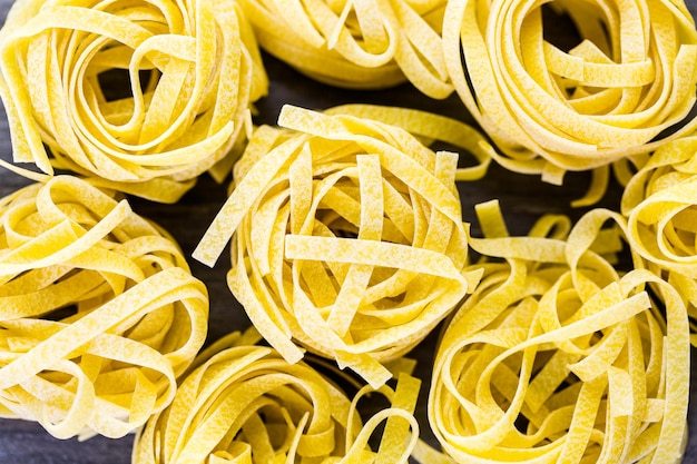 Macarrão de ninhos de fettuccine orgânico na placa de madeira.