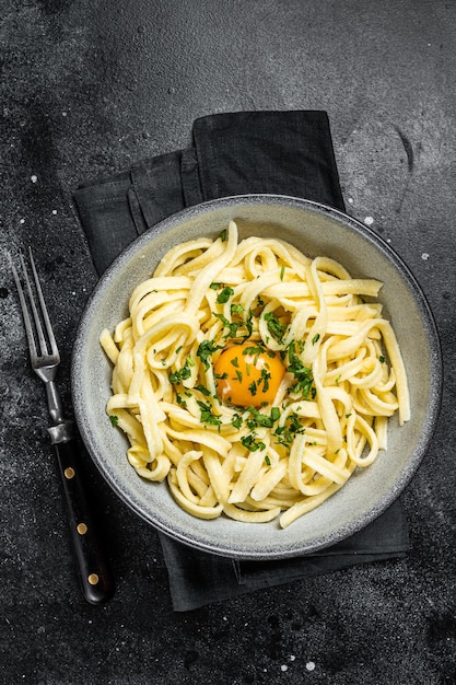 Macarrão de ovo spaetzle bávaro tradicional com manteiga e salsa fundo preto vista superior