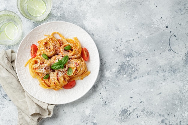 Macarrão de tagliatelle italiano apetitoso saboroso com molho de tomate queijo parmesão e manjericão no prato na mesa de luz Vista de cima horizontal Vista superior com espaço de cópia