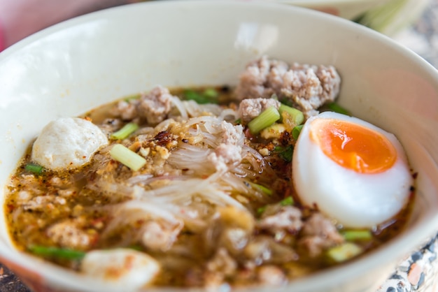 Macarrão de tom yum picante com carne de porco e ovo à venda no mercado de comida de rua tailandês ou restaurante na Tailândia