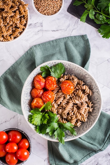 Macarrão de trigo sarraceno cozido, tomate e salsa em uma tigela Dieta alternativa Vista superior e vertical