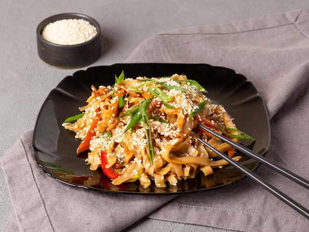 Macarrão de udon de comida vegetariana asiática com cogumelos gergelim e pimenta closeup Sementes de gergelim