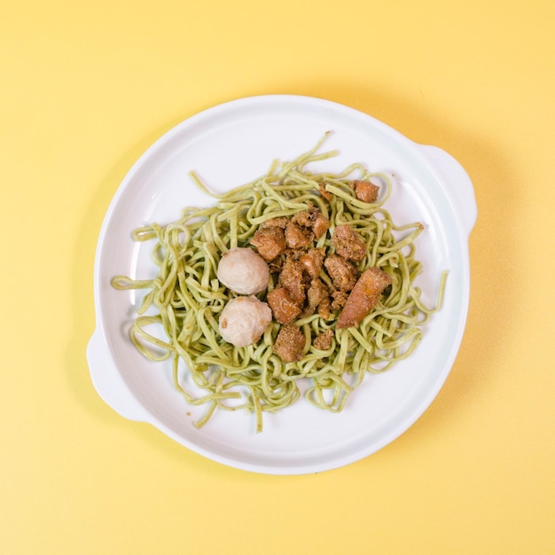 Macarrão de vegetais verdes em uma tigela com almôndegas asiáticas e curry de frango da indonésia