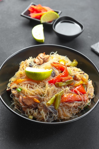 Macarrão de vidro com vegetais em uma tigela preta sobre fundo cinza comida asiática cozinha asiática asiática ou s