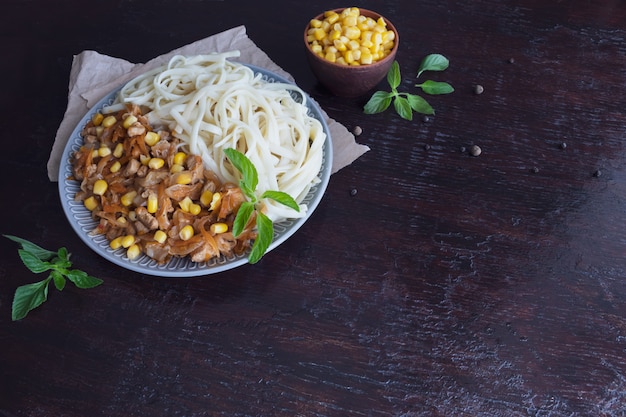 Foto macarrão delicioso com legumes em um prato grande. grãos de milho no banco.