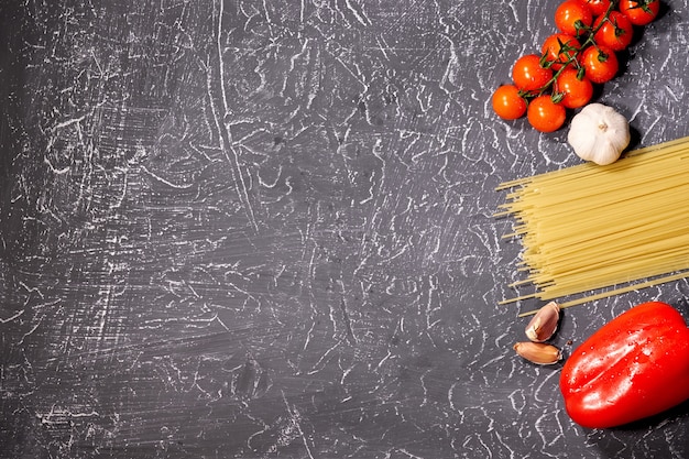 Macarrão disperso, alho, tomate, em fundo cinza