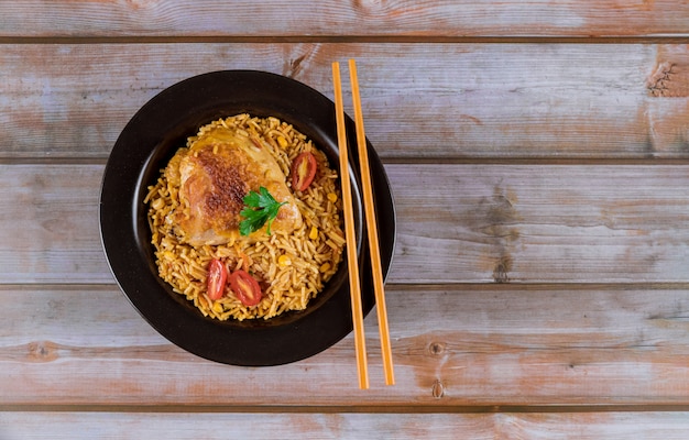 Macarrão e arroz com frango e legumes em uma tigela preta.