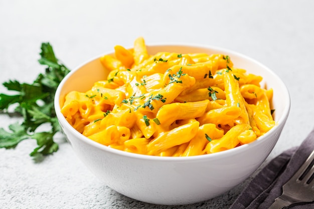 Macarrão e queijo em uma tigela branca, fundo cinza. Macarrão de queijo em uma tigela.