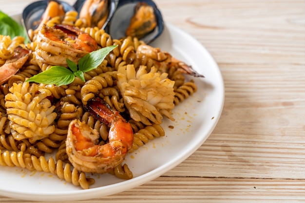 macarrão em espiral frito com frutos do mar e molho de manjericão - estilo de comida de fusão