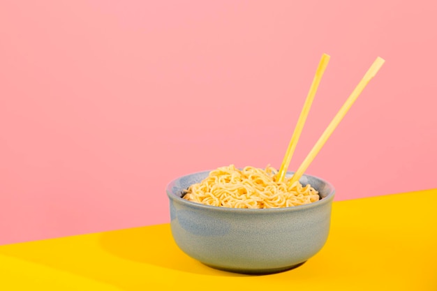 Foto macarrão encaracolado em tigela azul sobre fundo amarelo e rosa brilhante