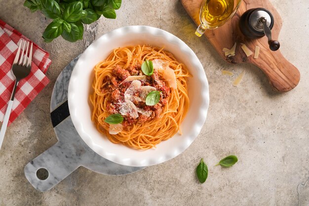 Macarrão espaguete à bolonhesa Saboroso e apetitoso espaguete italiano com molho à bolonhesa molho de tomate queijo parmesão e manjericão na chapa branca na pedra cinza ou fundo de mesa de concreto Vista superior