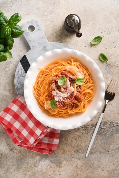 Macarrão espaguete à bolonhesa Saboroso e apetitoso espaguete italiano com molho à bolonhesa molho de tomate queijo parmesão e manjericão na chapa branca na pedra cinza ou fundo de mesa de concreto Vista superior