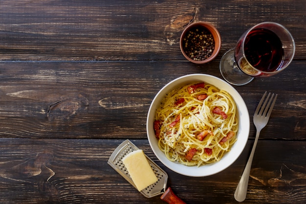 Macarrão espaguete carbonara em uma mesa de madeira. cozinha italiana. receita. estilo rústico. vinho.