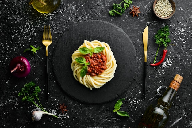 Macarrão espaguete com molho à bolonhesa e manjericão em um prato de pedra preta comida italiana vista superior espaço livre para texto