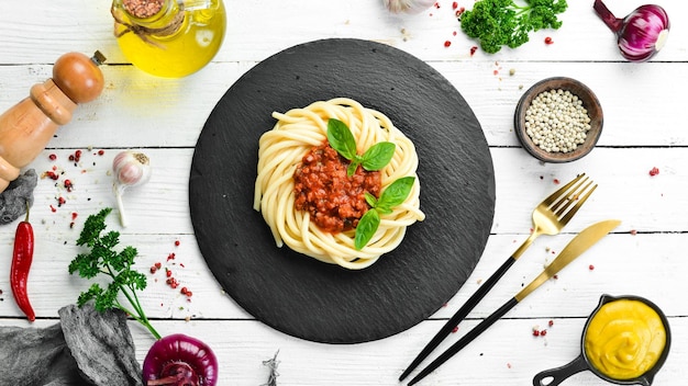 Macarrão espaguete com molho à bolonhesa e manjericão em um prato de pedra preta Comida italiana Vista superior Espaço livre para texto