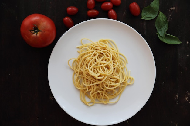 Macarrão espaguete com molho de tomate e manjericão em fundo escuro de madeira