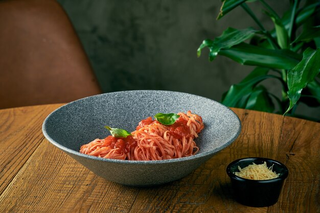 Macarrão espaguete com molho de tomate e manjericão em um prato cinza. cozinha italiana