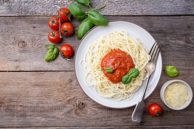 Macarrão espaguete com molho de tomate e manjericão sobre madeira