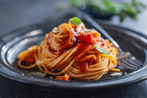 Macarrão espaguete com molho de tomate e queijo servido no prato.