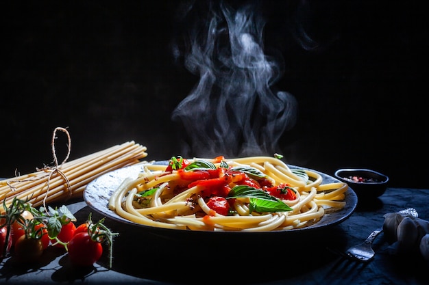 Macarrão, espaguete com molho de tomate em tigela preta.