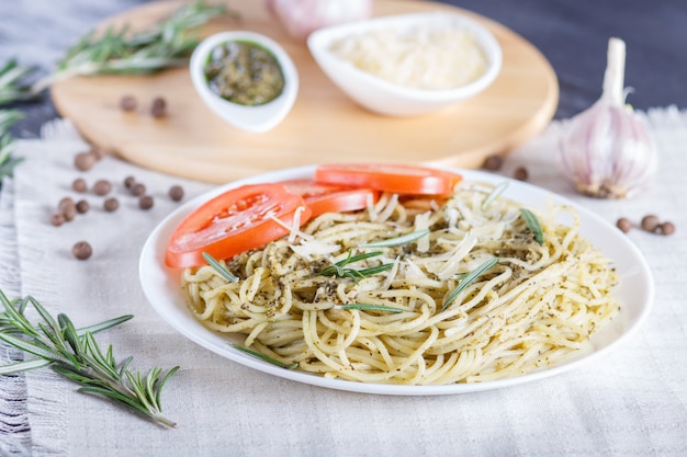 Macarrão espaguete com molho pesto, tomate e queijo sobre uma toalha de mesa de linho