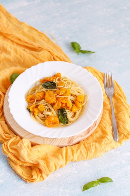 Macarrão, espaguete com tomate amarelo em prato branco