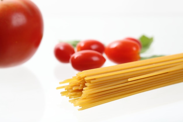 Macarrão espaguete cru com tomate e manjericão isolado no fundo branco