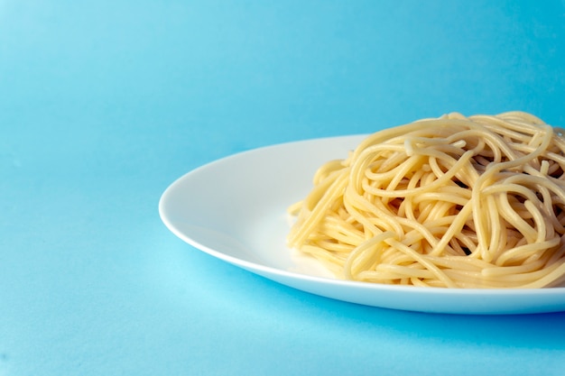 Macarrão espaguete em um prato branco sobre um fundo azul