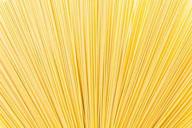Macarrão espaguete orgânico amarelo em um fundo branco.