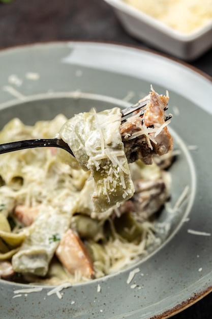 Macarrão fettuccine alfredo com cogumelos e frango frito ao molho cremoso de queijo. Massa Tagliatelle. Fundo de receita de comida. Fechar-se.