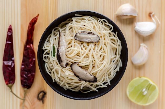 Macarrão frito em tigela preta na mesa de madeira, comida de rua tailandês