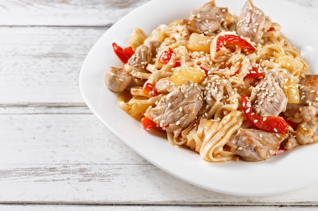 Macarrão frito udon com carne de porco e abacaxi na mesa de madeira. pad thai