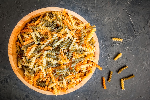 Macarrão fusilli colorido na tigela de madeira