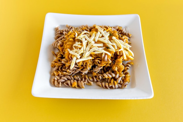 Macarrão Fusilli com molho de abóbora e queijo colonial em fundo amarelo