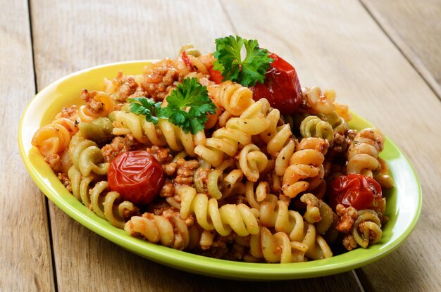 Macarrão fusilli com molho de carne de tomate à bolonhesa na mesa da cozinha